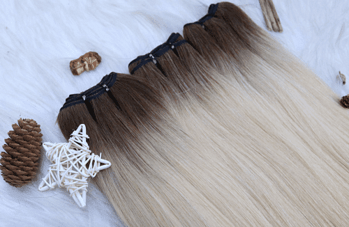 Ombre hair extensions on fluffy surface with pinecone and woven star.